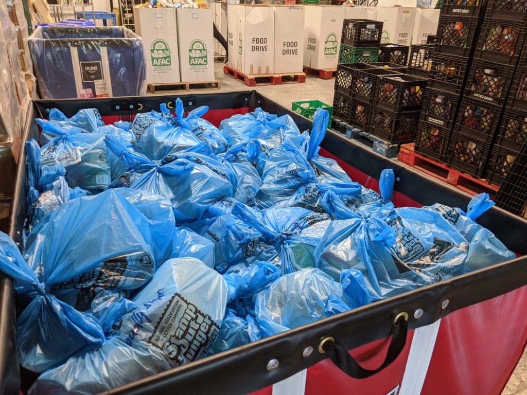 blue bags filled with food in a red bin in a warehouse