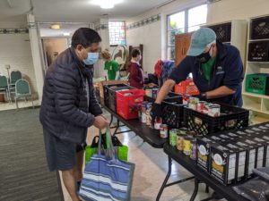 client selecting canned food with the help of a volunteer